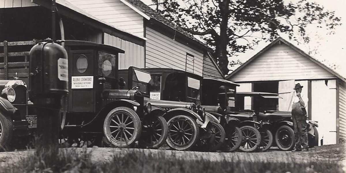 Row of old trucks outside the Crawford House that read "Allen E. Crawford Wholesale Butcher"
